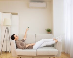 Young woman switching on air conditioning at her house